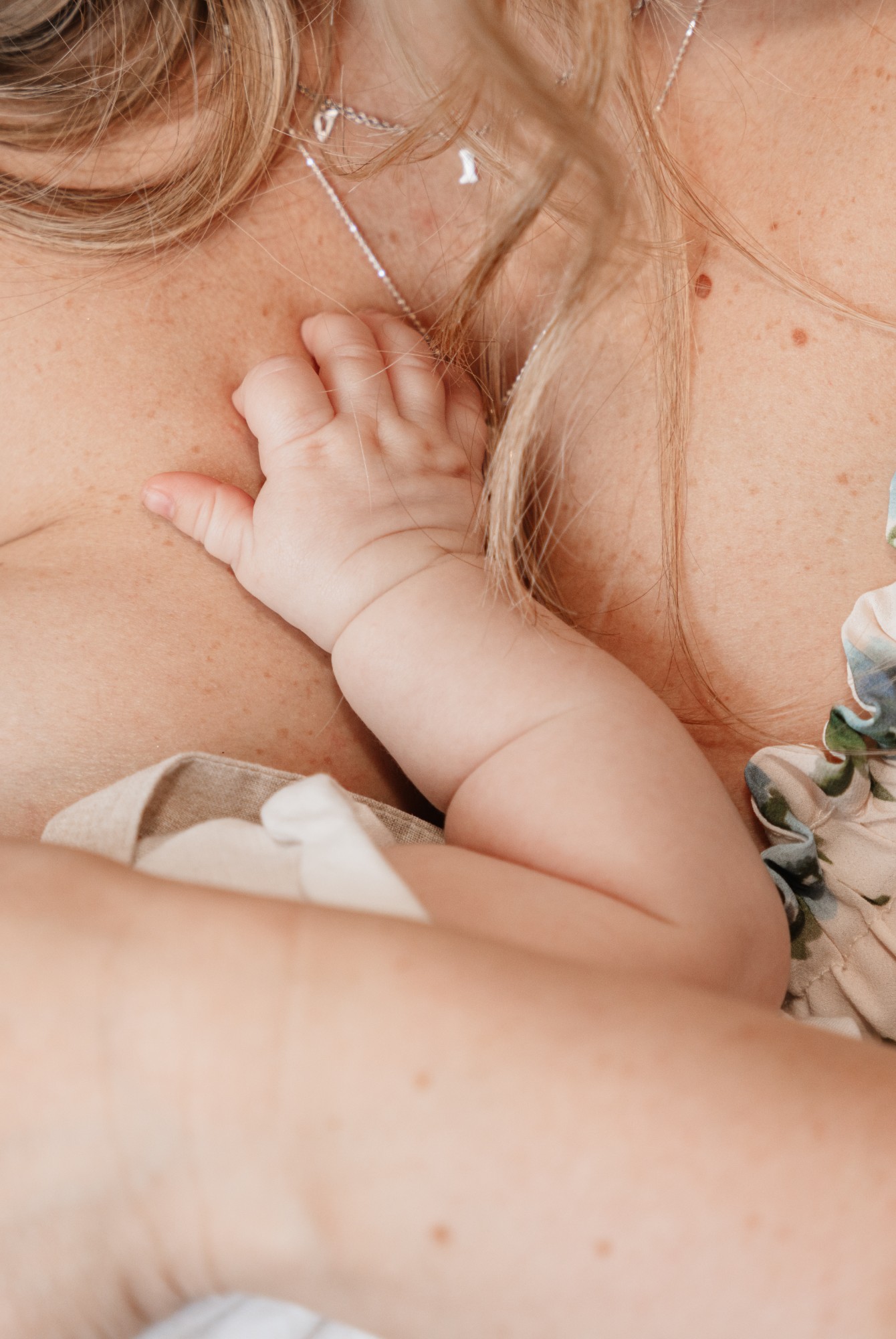 A newborn's hand resting on a mother's chest