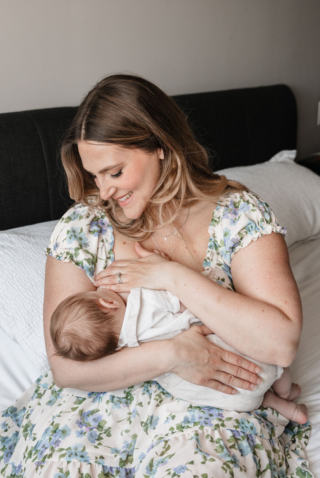 Melanie smiling down at her nursing newborn